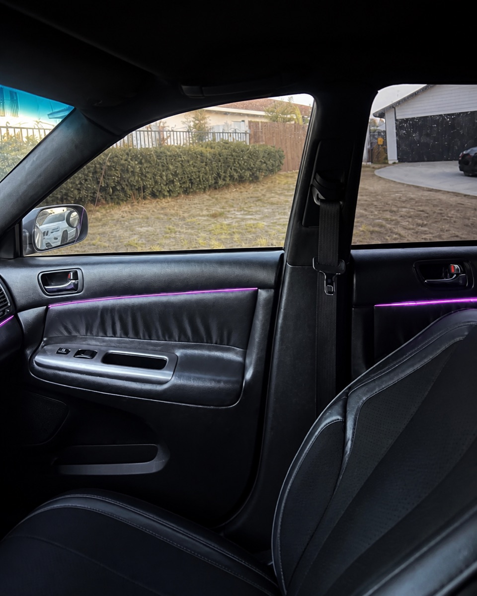 Pink ambient lighting along the front and rear passenger doors in daylight